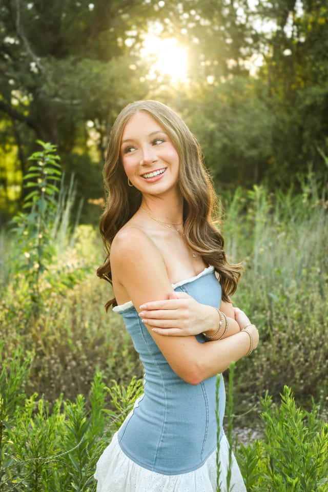 Senior portrait in a blue corset top, golden hour in a grassy field