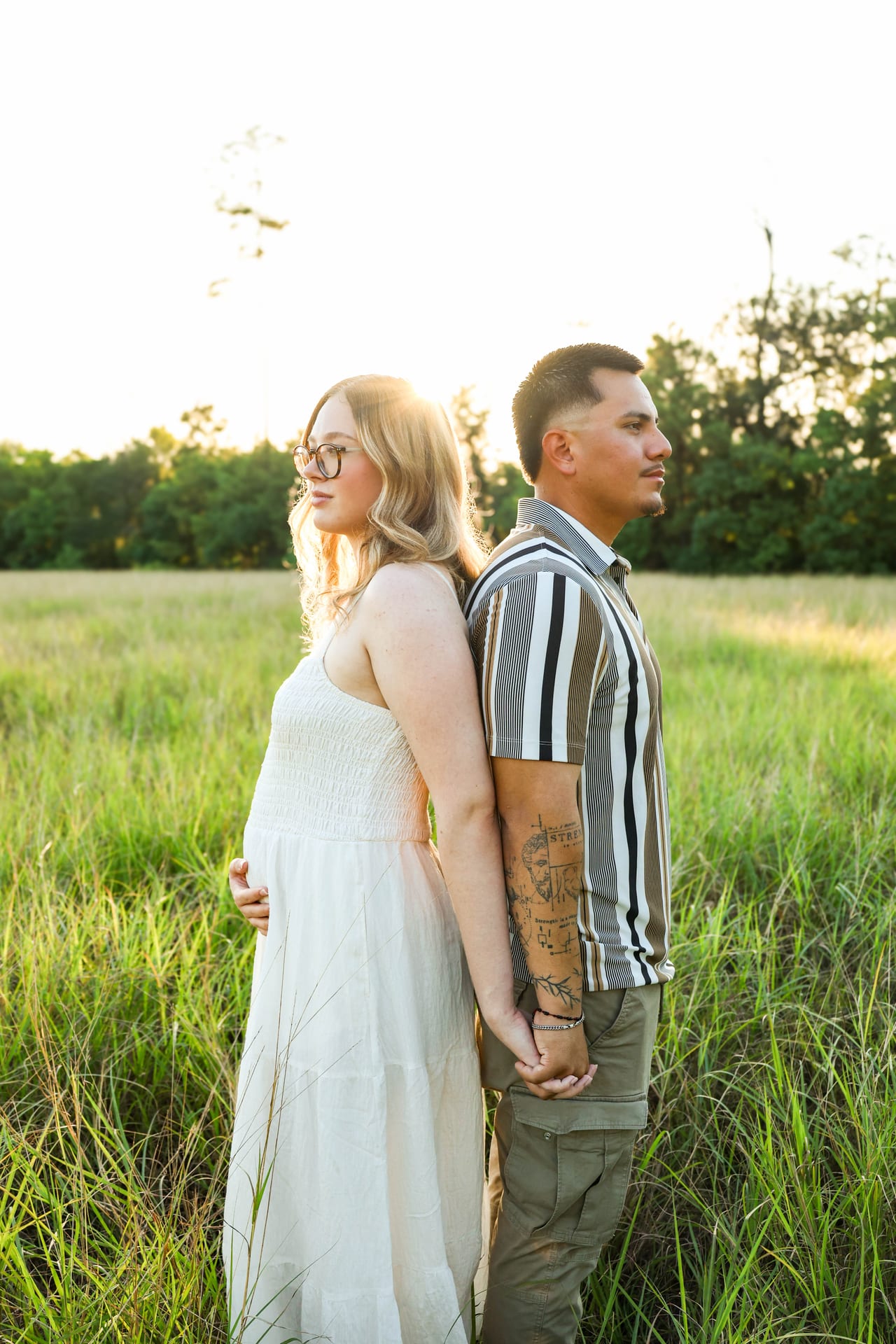 Couple back-to-back in a sunlit field