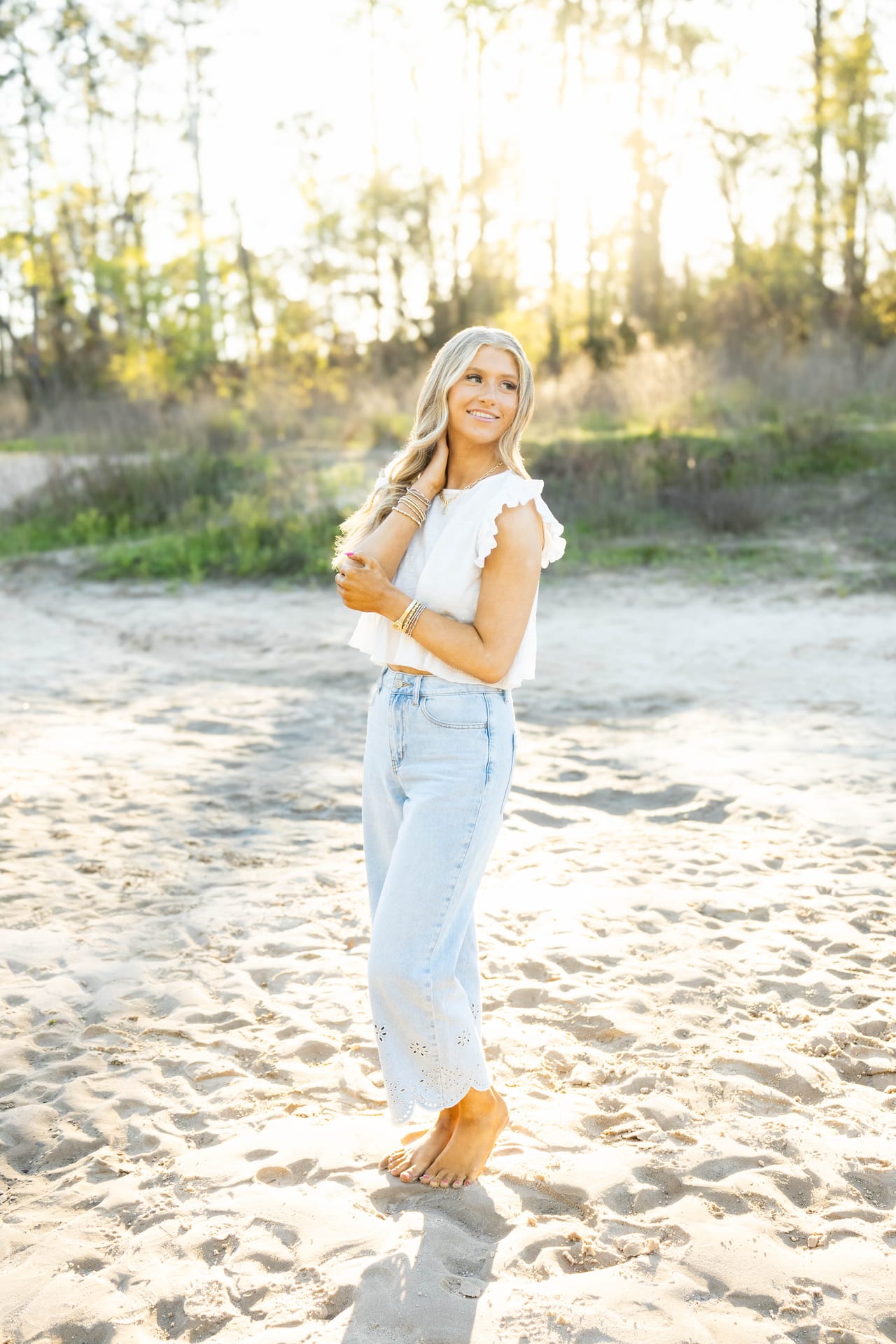 Senior in white top and jeans on a sandy path