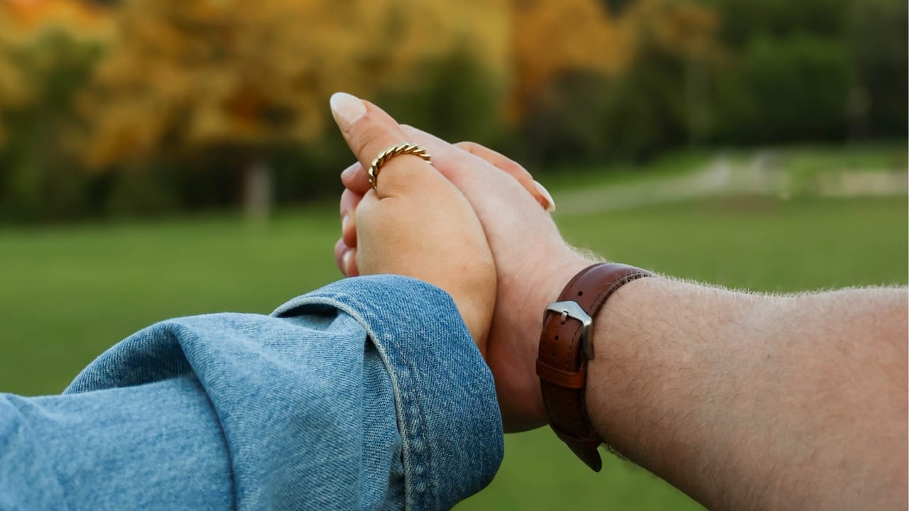 Close-up of a couple holding hands in a field
